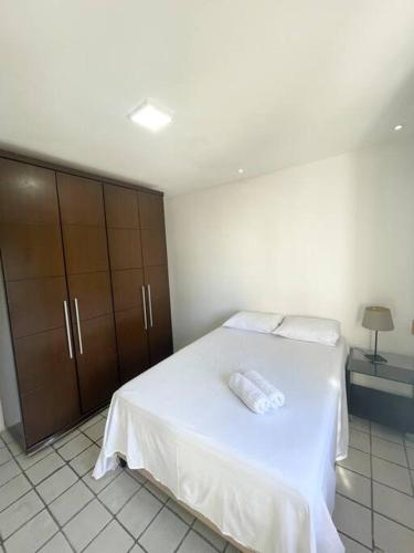 um quarto com uma cama branca e armários de madeira em APARTAMENTO NO MELHOR DE BOA VIAGEM no Recife