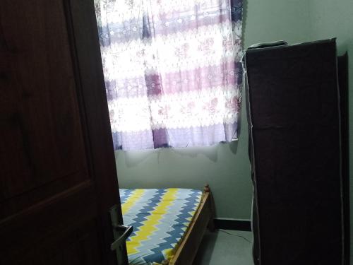 1 dormitorio con ventana y 1 cama con cortina en Misyie's HomeStay, en Sao Hill