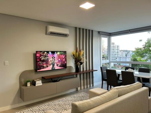 a living room with a couch and a tv on a wall at Apartamento em Bento Gonçalves in Bento Gonçalves