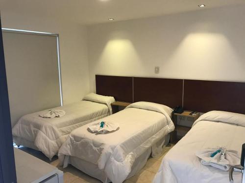 a hotel room with three beds and a mirror at Hotel internacional in Termas de Río Hondo