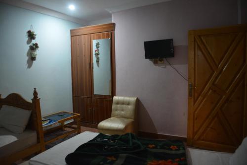 Schlafzimmer mit einem Bett, einem TV und einem Stuhl in der Unterkunft PC Green Hotel, Mahandri, Kaghan in Mingora