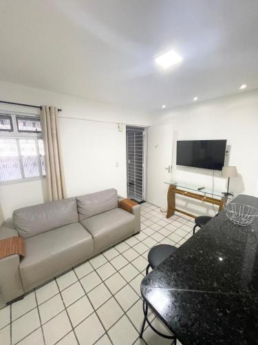 uma sala de estar com um sofá e uma televisão de ecrã plano em APARTAMENTO NO MELHOR DE BOA VIAGEM no Recife