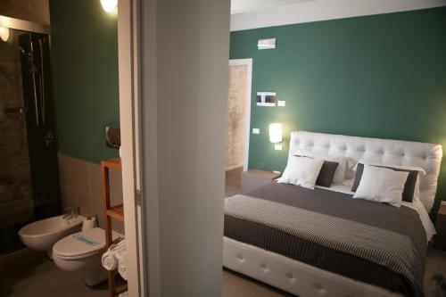 ein Schlafzimmer mit einem Bett, einem WC und grünen Wänden in der Unterkunft B&B Agorà in Bitetto