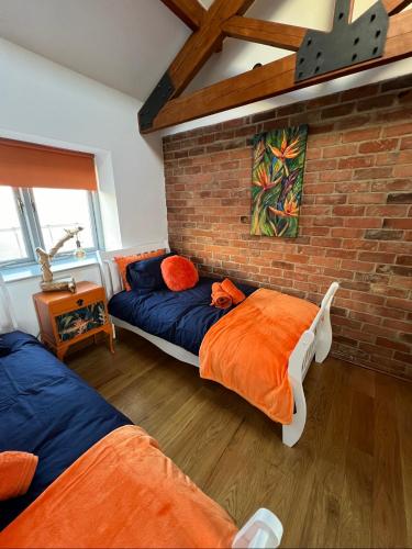 a bedroom with two beds and a brick wall at Aplanty House: A Hidden Gem in The Heart of The Fens in Wisbech