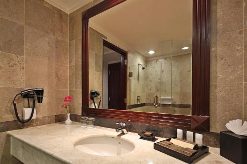 La salle de bains est pourvue d'un lavabo et d'un grand miroir. dans l'établissement Aryaduta Pekanbaru, à Pekanbaru