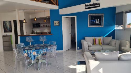 un salon avec une table et un mur bleu dans l'établissement APPARTEMENT T3 vue RHUNE, à Saint-Jean-de-Luz
