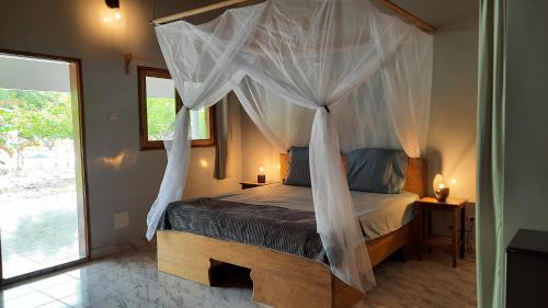 1 dormitorio con cama con dosel y mosquiteras en Chez Nous Chez Vous, en Toubakouta