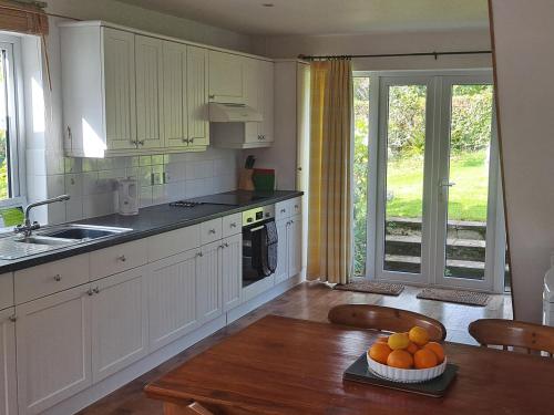 uma cozinha com armários brancos e uma mesa com laranjas em Hayway em South Brent