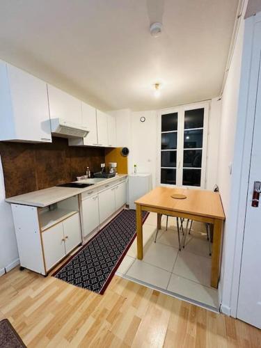 une cuisine avec des armoires blanches et une table en bois dans l'établissement Appart T3 centre ville Castres, à Castres