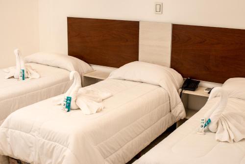 two beds in a room with white sheets at Hotel internacional in Termas de Río Hondo