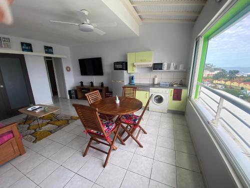 een keuken met een tafel en stoelen en een balkon bij Ti Mélissa in Les Trois-Îlets