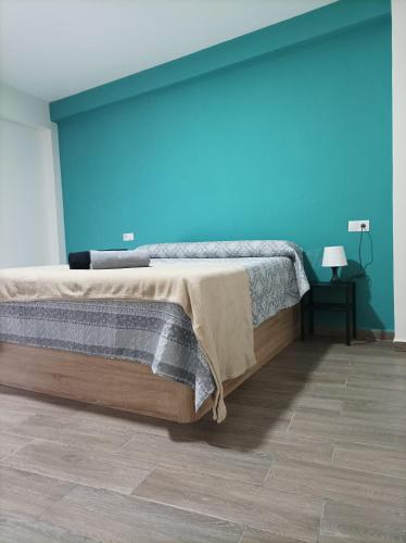 1 dormitorio con 1 cama grande y pared azul en Alojamiento Alisson, en Villena
