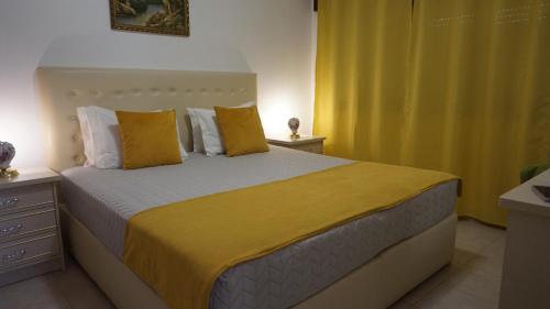 a bedroom with a large bed with yellow sheets and pillows at Apartamentos na Quinta Altavista do Carvalhal in Zambujeira do Mar