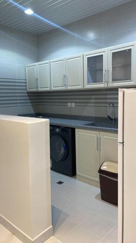 a kitchen with white cabinets and a washer and dryer at شقق ثمانين بارك 2 in Khamis Mushayt