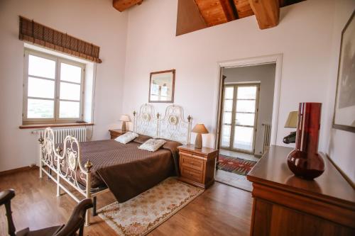 a bedroom with a bed and a dresser and two windows at La Casa di Alice in Villa San Secondo