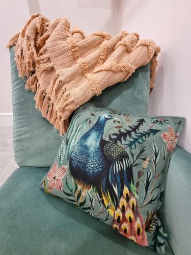 a pillow with a peacock on it sitting on a couch at The Snug Lytham in Lytham St Annes