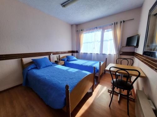 1 dormitorio con 2 camas, mesa y ventana en ALERCE NATIVO HOTEL, en Castro