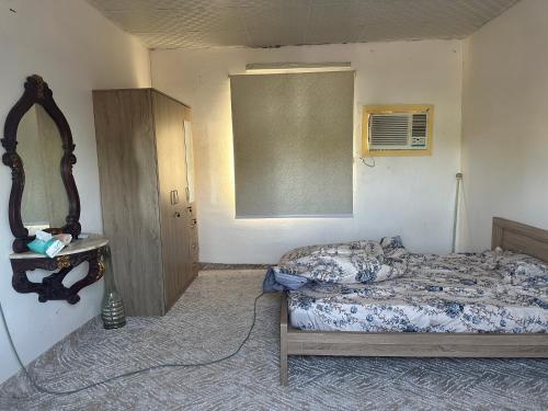 a small bedroom with a bed and a mirror at استراحة الريان in Umm Lujj