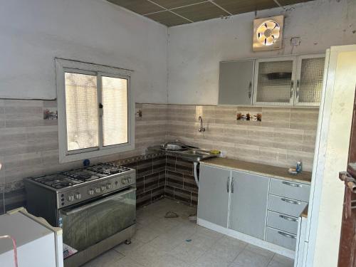 een keuken met een fornuis, een wastafel en een raam bij استراحة الريان in Umm Lajj