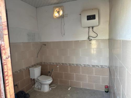 een badkamer met een toilet en een doos aan de muur bij استراحة الريان in Umm Lajj