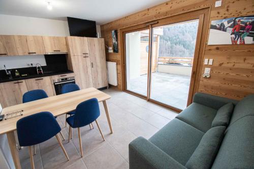 a living room with a couch and a table with chairs at Dans résidence neuve LE SNOW ROC sur les pistes, grand studio cosy 5 pers avec terrasse panoramique, SAUNA, WIFI in Saint-Jean-dʼAulps