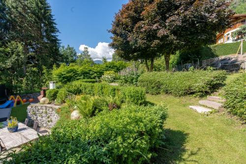 a garden with bushes and a stone wall at Hotel Bella di Bosco in Malè