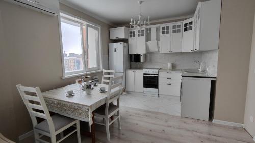 a kitchen with a table and chairs and a white refrigerator at Kamal Apart in Prigorodnyy