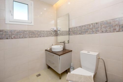 a white bathroom with a toilet and a sink at Elli Garden View - Spacious Fully Equipped Apartment in Kremasti