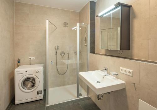 a bathroom with a sink and a washing machine at SweetHome - Poing Apartments in Poing