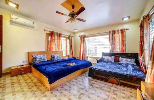 a bedroom with two beds and a ceiling fan at Abbey Cottage in Dharamshala