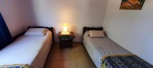 2 Betten in einem Zimmer mit einer Lampe auf einem Tisch in der Unterkunft Casa V.Giardino pileta y cochera in Villa Giardino