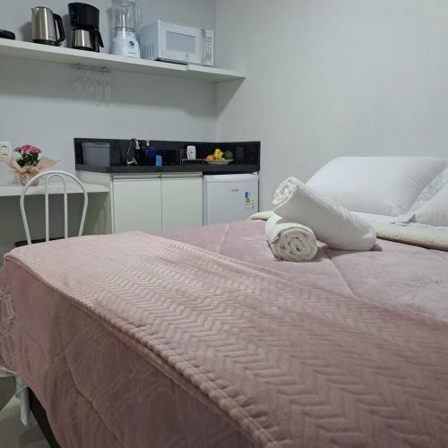 a bedroom with a bed with a pink blanket and a kitchen at Casa Missões Dill Haus 1 in Gramado