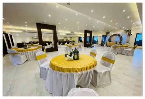 um salão de banquetes com uma mesa amarela e cadeiras brancas em Spring Vine Shrinagar em Srinagar