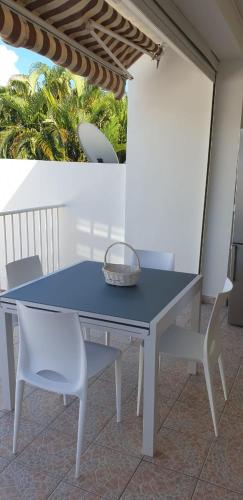 a blue table and two white chairs on a patio at COSY Tamarins 2 plage à quelques mètres à pied in Sainte-Anne