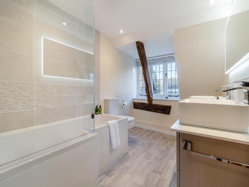 a white bathroom with a tub and a sink at The Farmhouse - Uk45894 in Banham