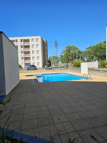 a swimming pool with a building in the background at Apartamento full equipado in Temuco