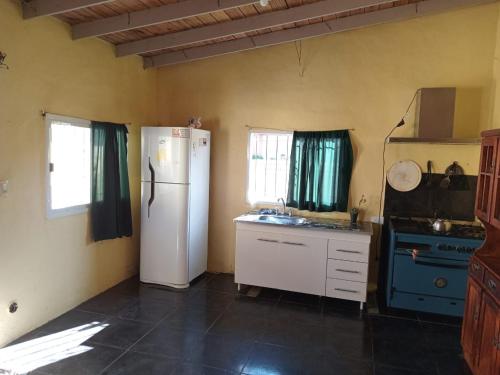 cocina con heladera blanca y fogones en Casa Amarilla Beach en Villa Gesell
