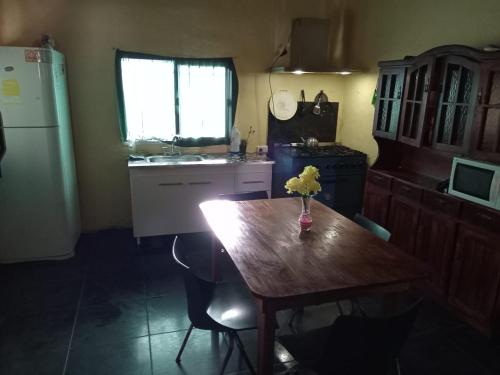 una cocina con una mesa de madera con un jarrón de flores. en Casa Amarilla Beach en Villa Gesell