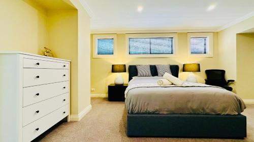 a bedroom with a bed and a dresser and two windows at Three Monkeys Residence in Kellyville