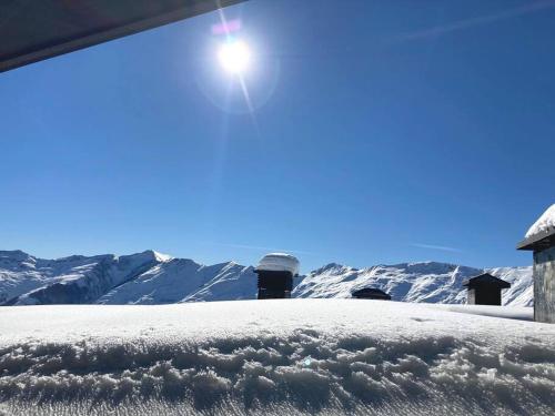 a snow covered roof of a house with mountains in the background at Roshka Apartment 108 in Gudauri