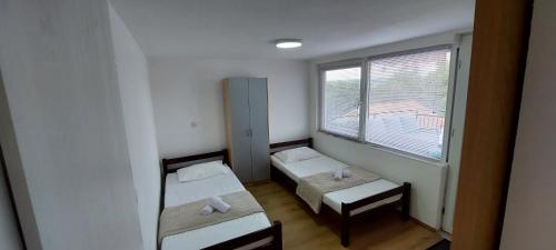 Cette petite chambre comprend 2 lits et une fenêtre. dans l'établissement Sydney Apartment, à Bilice