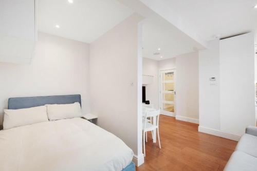 biała sypialnia z łóżkiem i stołem w obiekcie Beaufort Gem Chelsea Apartment w Londynie