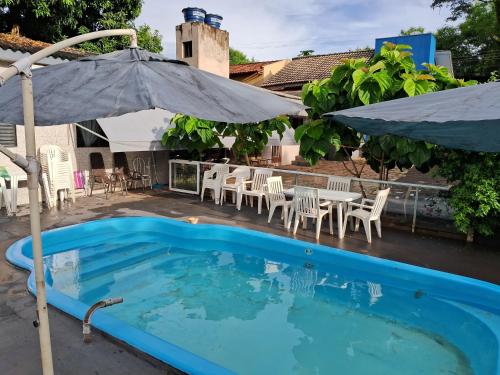 einen Pool mit Sonnenschirm, Tischen und Stühlen in der Unterkunft Iguaçu House in Foz do Iguaçu