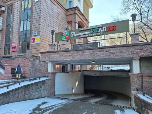 a woman walking through a tunnel in front of a building at ЖК Сункар in Almaty