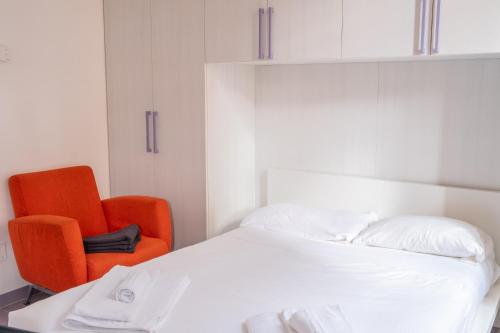 a bedroom with a bed and an orange chair at Casa Moro, monolocale moderno nel centro storico in Crema