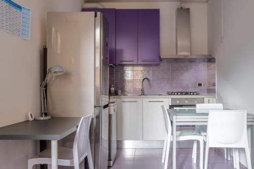 a kitchen with purple cabinets and a table and chairs at Casa Moro, monolocale moderno nel centro storico in Crema