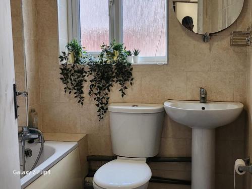 a bathroom with a toilet and a sink and a mirror at Cozy 2 bed Flat/Apt in East London- Nice Estate. in Goodmayes