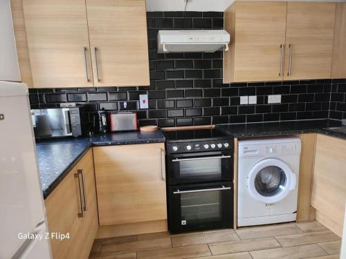 uma cozinha com uma máquina de lavar roupa e uma máquina de lavar louça em Cozy 2 bed Flat/Apt in East London- Nice Estate. em Goodmayes