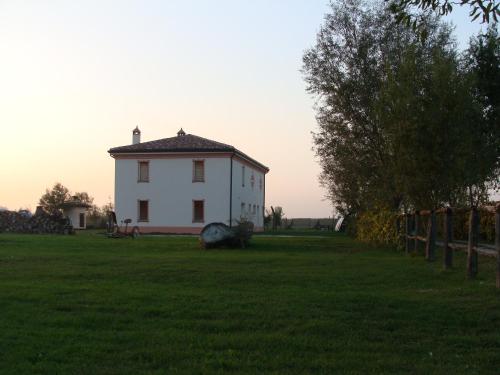 a white house in a field with a tree at Antico Casale dei Sogni agriturismo in Lugo