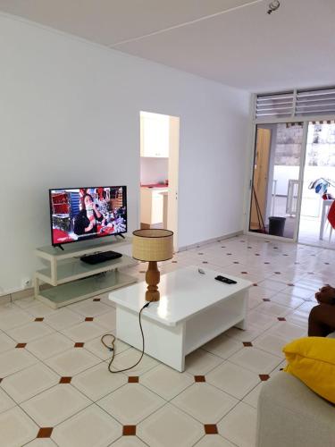 a living room with a table and a tv at COSY Tamarins 2 plage à quelques mètres à pied in Sainte-Anne